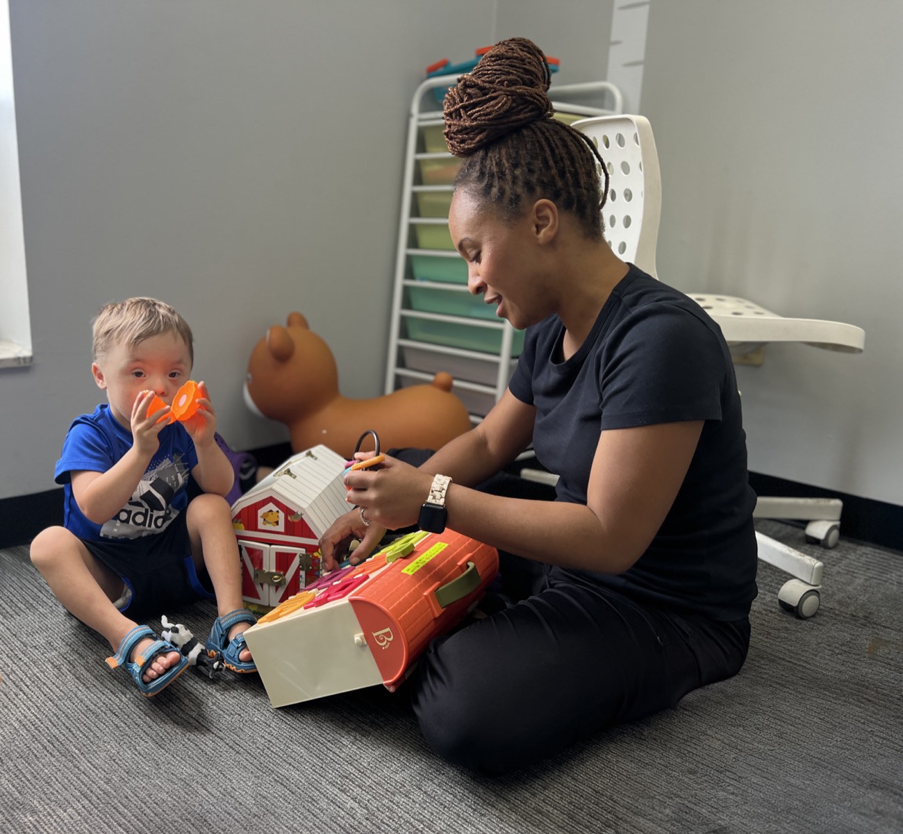 An UpWords speech therapist sitting on the floor playing with a young child during a therapy session